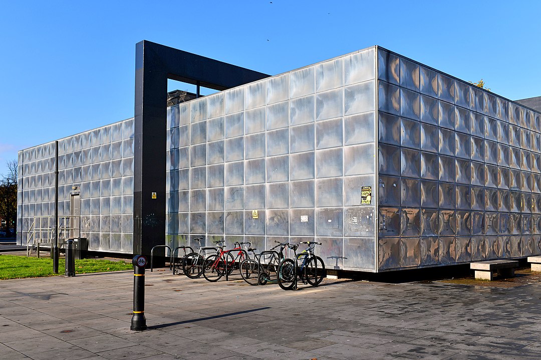 A large boxy building with bicycles parked in front